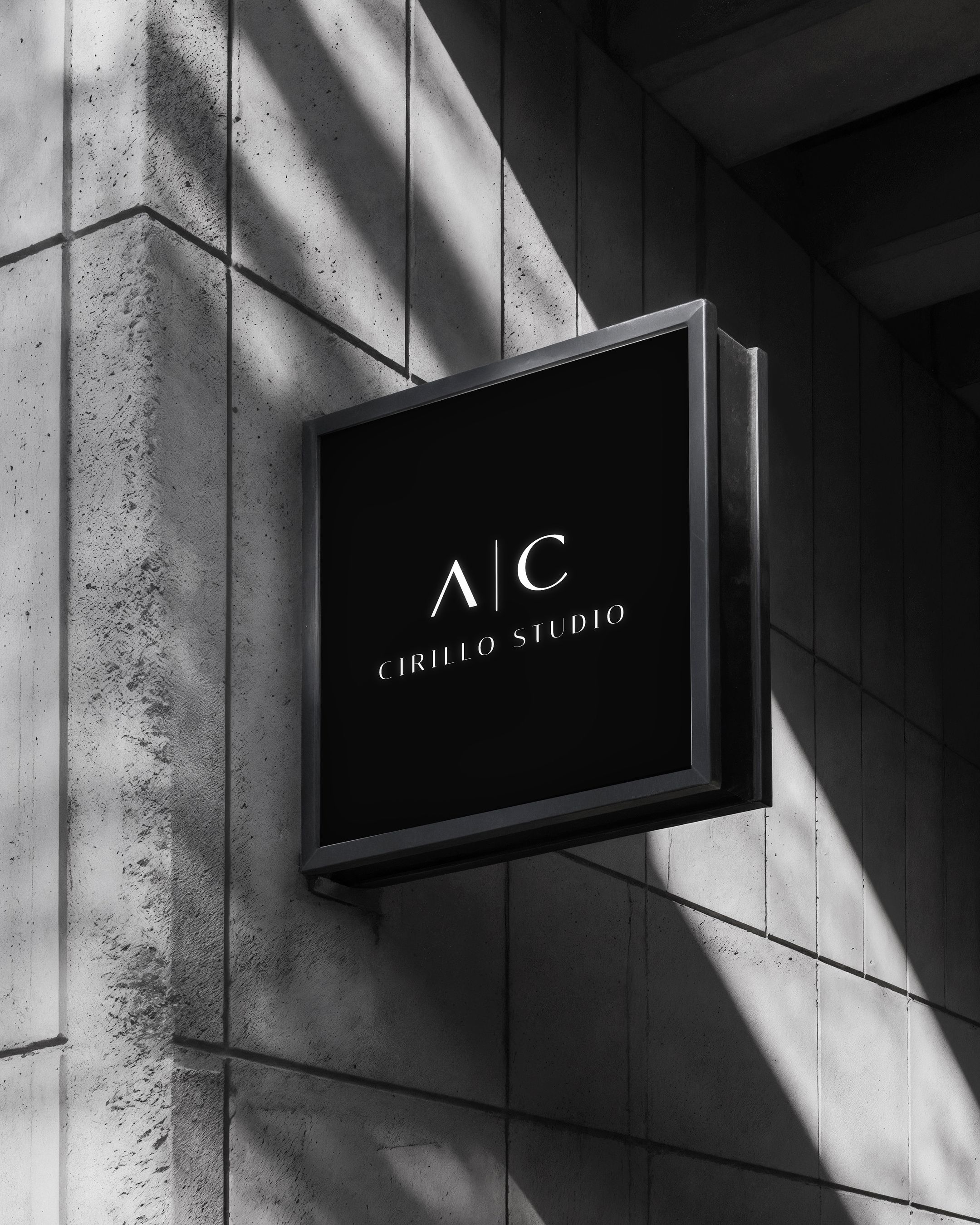 Insegna nera con il logo bianco illuminato di Cirillo Studio su un muro di cemento.